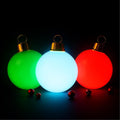Three glowing ornament balls in green, white and red with gold caps