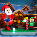Santa putting on a green with an elf holding the flag, inflatable in front of a lit house