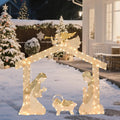 Warm white lighted nativity stable with an angel on top and the Holy Family in the snow