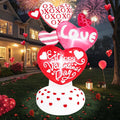 Stack of heart inflatables reading XOXO, Love and Happy Valentine's Day on a lawn at night