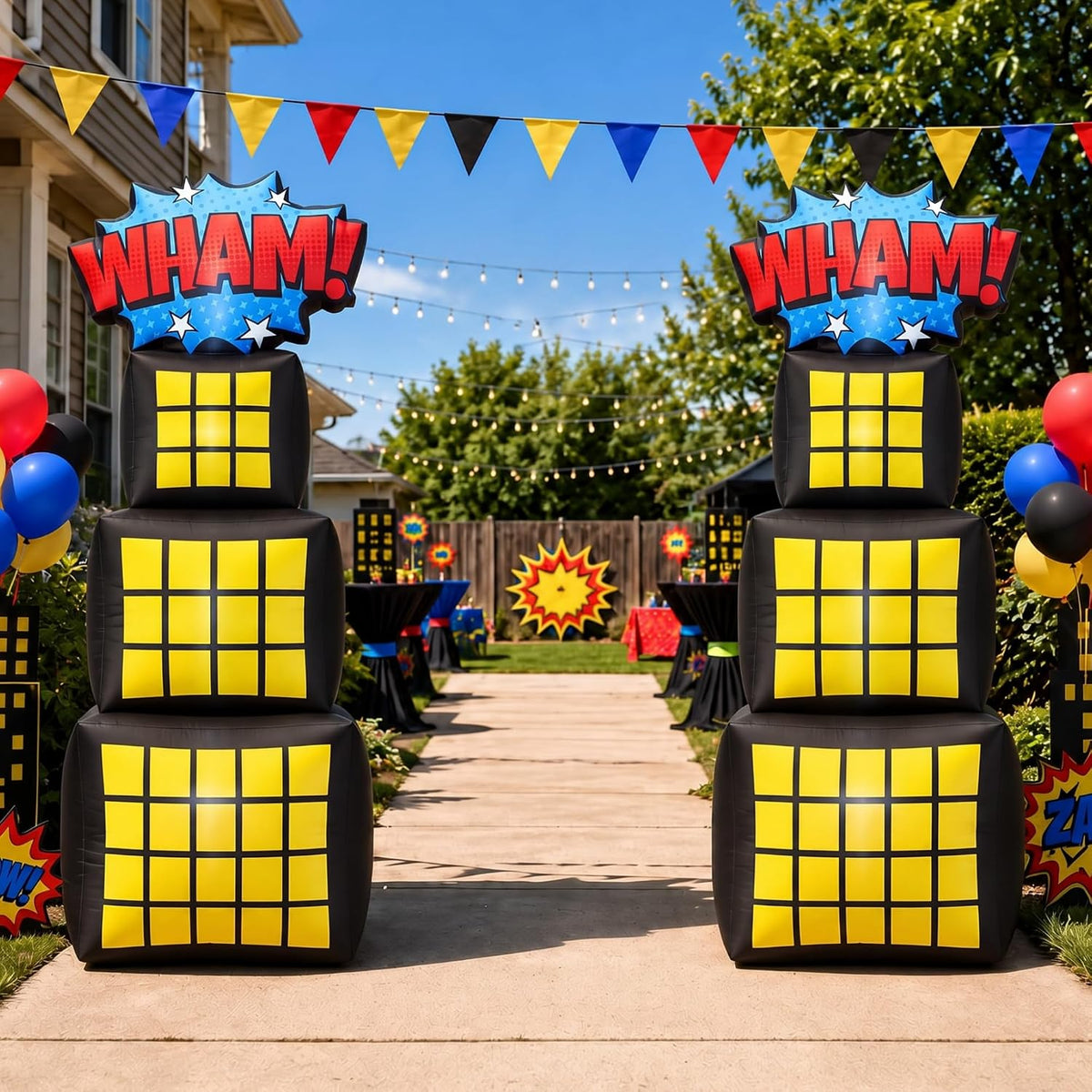 Two comic book city tower inflatables with yellow windows and WHAM signs lining a party path