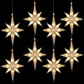 Several warm white Bethlehem star lights hanging on cords against a black background