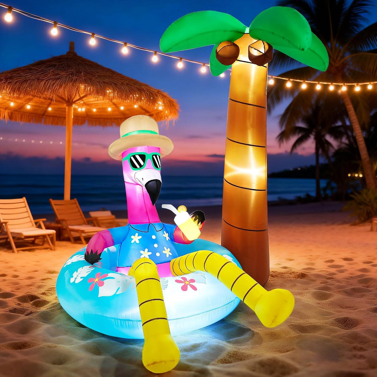 Pink flamingo in sunglasses on a blue pool float beside a lit palm tree inflatable on a beach at night
