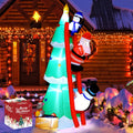 Green Christmas tree inflatable with Santa on a red ladder, a penguin on top and a snowman below