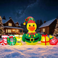 Yellow duck in an elf costume beside JOY letters, a candy cane and gifts on a snowy lawn at night